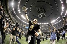 a football player is holding his helmet up in the air with other people around him