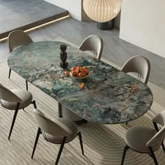 a dining table with chairs around it and a bowl full of fruit on the table