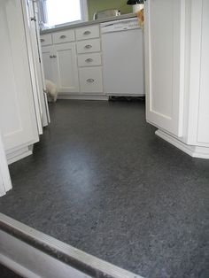 an empty kitchen with white cabinets and gray flooring