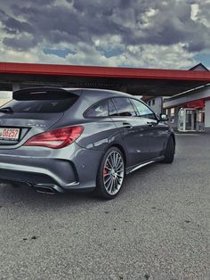 the rear end of a mercedes cla parked in front of a gas station with cloudy skies