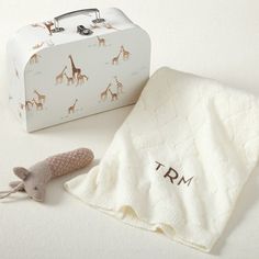 a white suitcase with giraffes on it next to a towel and toy