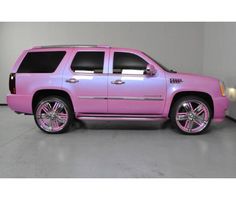 a pink suv parked in a garage with chrome wheels and rims on the tires