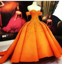 an orange dress sitting on top of a table next to a mannequin's head