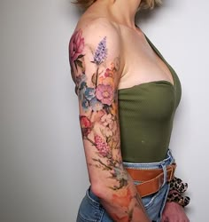 a woman with a flower tattoo on her arm and shoulder is posing for the camera