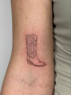 a small boot tattoo on the back of a woman's right arm and leg