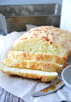 a loaf of bread sitting on top of a piece of paper next to a cup