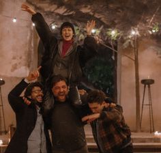 three men are posing for the camera with their arms in the air and one man is holding his head up