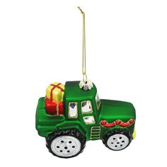 a green christmas ornament with a tractor and presents hanging from it's back