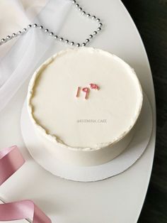 a white cake with the number 19 on it sitting on a plate next to pink ribbon