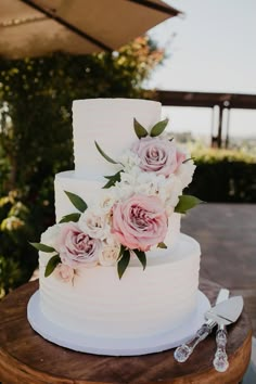 a white wedding cake with pink flowers and greenery