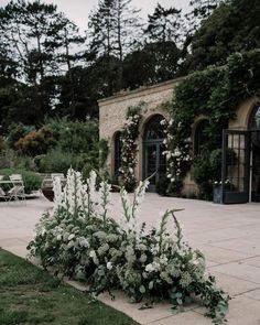 some white flowers and greenery in front of a building