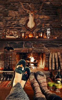 a person with their feet up in front of a fireplace filled with candles and deer heads