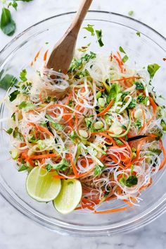 a glass bowl filled with shredded carrots, cilantro, and green onions