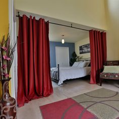 a bedroom with red curtains and a white bed in it's centerpieces