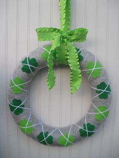 a green and white wreath hanging on the side of a door with shamrocks painted on it