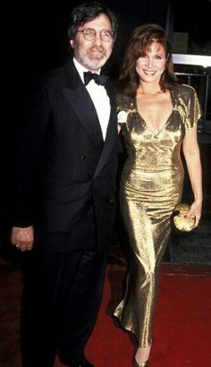 a man and woman in formal wear standing on a red carpet