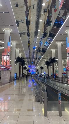 an empty airport terminal with palm trees on the ceiling and luggage carousels in the background