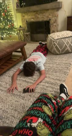 a person laying on the floor in front of a christmas tree