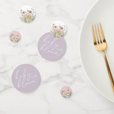 baby shower stickers on a plate next to a fork and napkin with the words baby in bloom