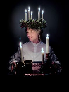 a woman with candles on her head holding a tray