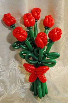 a bunch of red flowers sitting on top of a white cloth covered table next to a wall