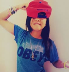 a young woman wearing a red hat and blue t - shirt is posing for the camera