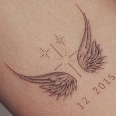 a close up of a tattoo on the back of a person's arm with wings