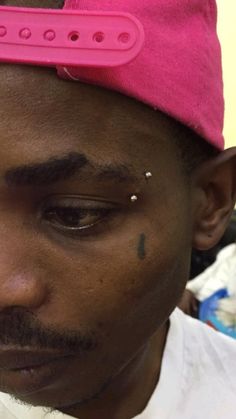 a close up of a person wearing a pink hat and piercings on his forehead