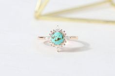 an image of a turquoise stone ring on a white table with gold and diamond accents