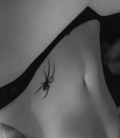 a black and white photo of a woman with a spider tattoo on her side belly