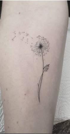 a small dandelion tattoo on the back of a woman's left thigh