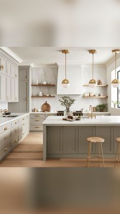 a large kitchen with white cabinets and gold accents on the counter tops, along with two stools