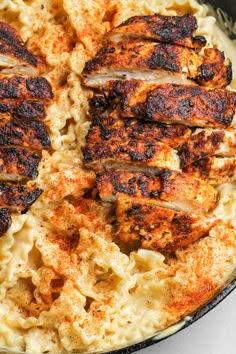 chicken and macaroni dish in a skillet on a white counter top with a fork