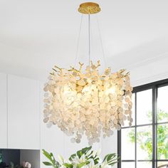 a chandelier hanging over a dining room table with flowers in the vases