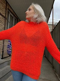 a woman with white hair wearing an orange sweater