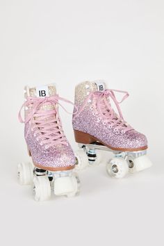 pair of pink roller skates with sequins and laces on white background