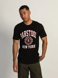 a man standing in front of a white wall wearing a black t - shirt with barstod new york on it