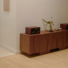 two wooden speakers sitting on top of a table next to a vase with flowers in it