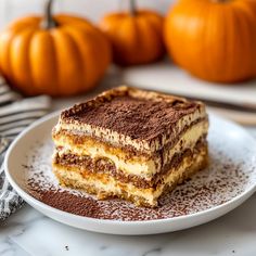 a piece of cake sitting on top of a white plate next to two pumpkins