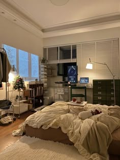 an unmade bed sitting in a bedroom next to a tv on top of a dresser