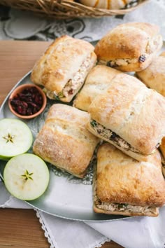 several pastries on a plate with apples and cranberry sauce in the background