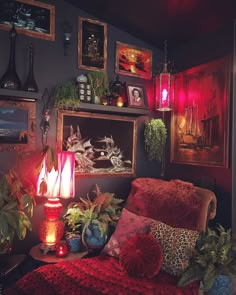 a living room filled with lots of plants and pictures hanging on the wall above it