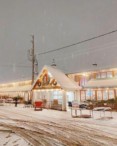 a small white building with christmas lights on it's roof in the middle of a snowy street