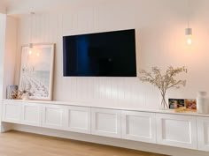 a flat screen tv mounted to the side of a white wall in a living room