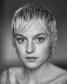 a black and white photo of a woman with blonde hair looking at the camera,