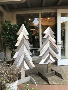 three wooden christmas trees sitting in front of a store