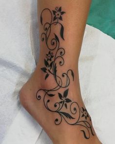 a woman's foot with black flowers and vines on the bottom of her leg