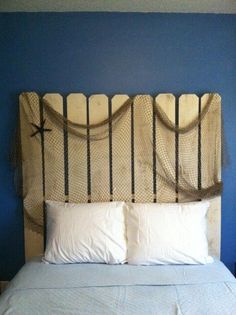 a bed with blue walls and white pillows in a room that has a headboard made out of wood sticks