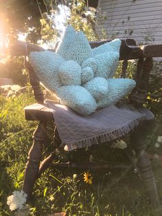 a chair that is sitting in the grass with some pillows on it's back