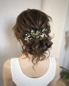 the back of a woman's head wearing a white top with flowers in her hair